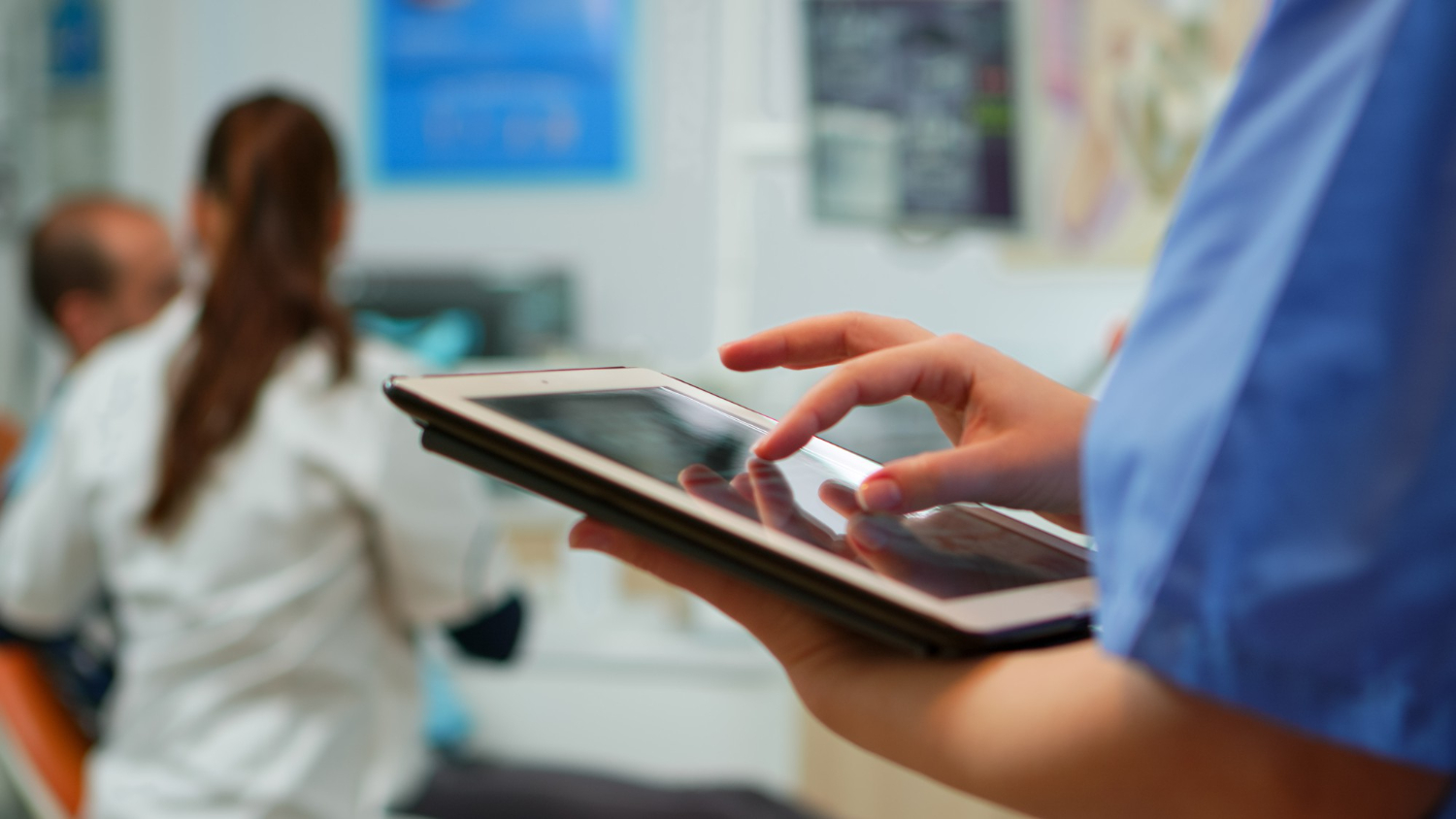 close-up-nurse-holding-typing-tablet-standing-stomatologic-clinic-while-doctor-is-working-with-patient-background-using-monitor-with-chroma-key-izolated-pc-key-mockup-pc-display (1)