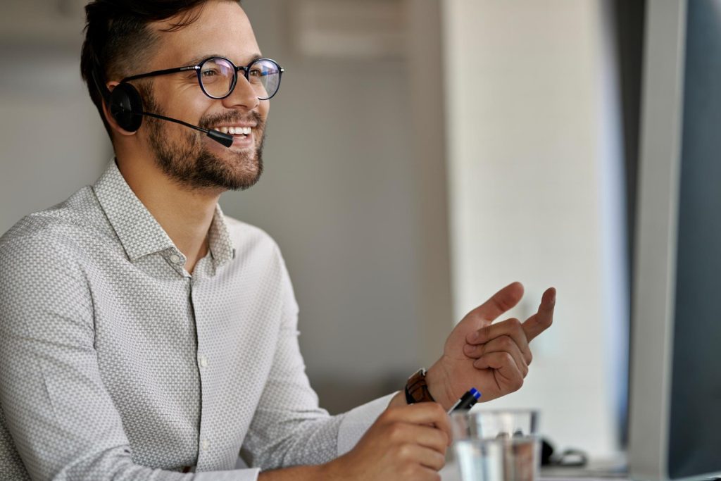 happy-call-center-agent-using-computer-while-communicating-with-clients-working-office